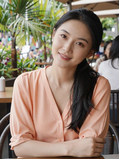 Mei Xin, 26-year-old Chinese woman from Guangzhou in a peach blouse at an outdoor cafe open to international dating